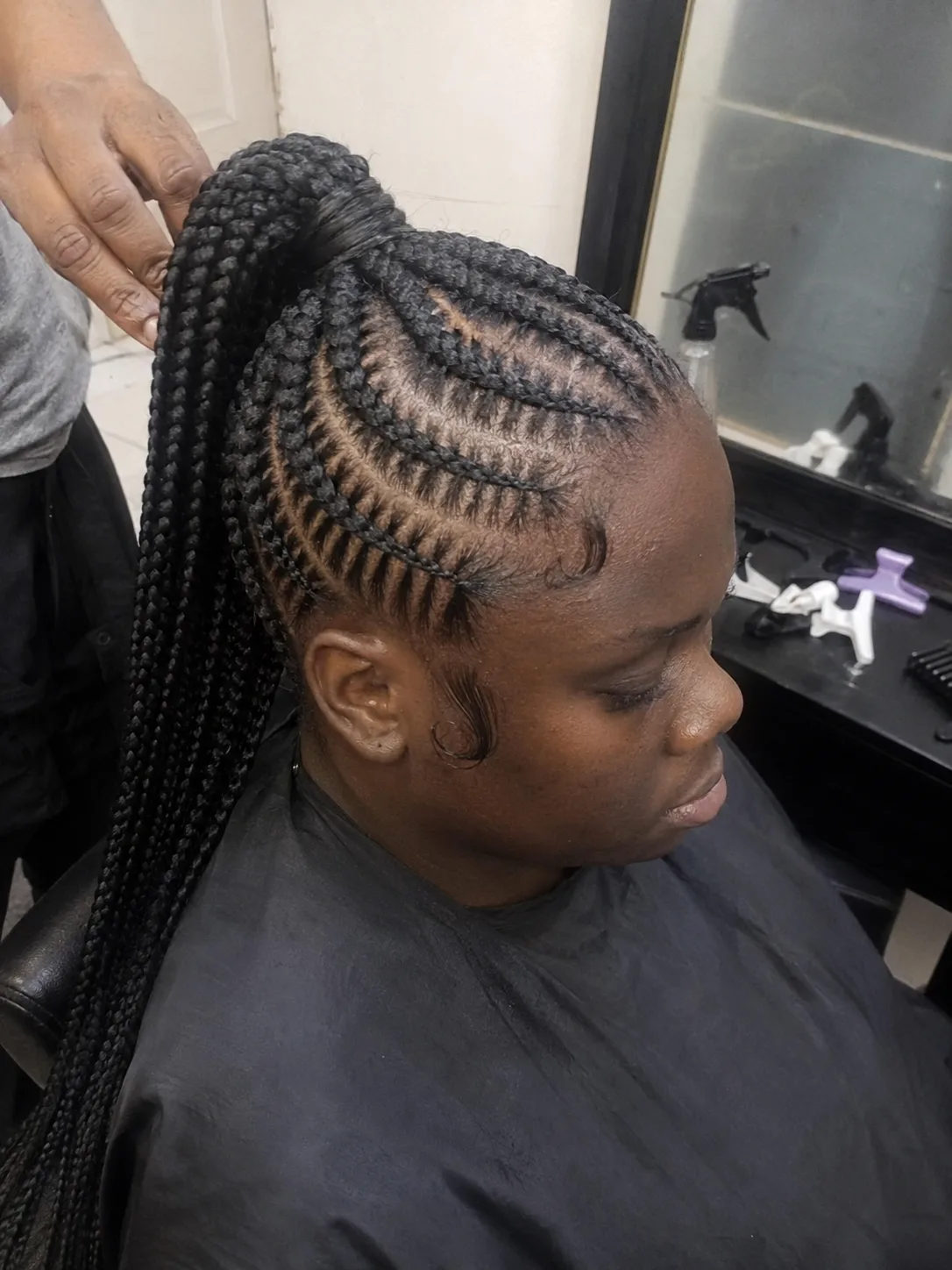 Stylist applying texturizing spray to separated sections of dry hair for braid grip
