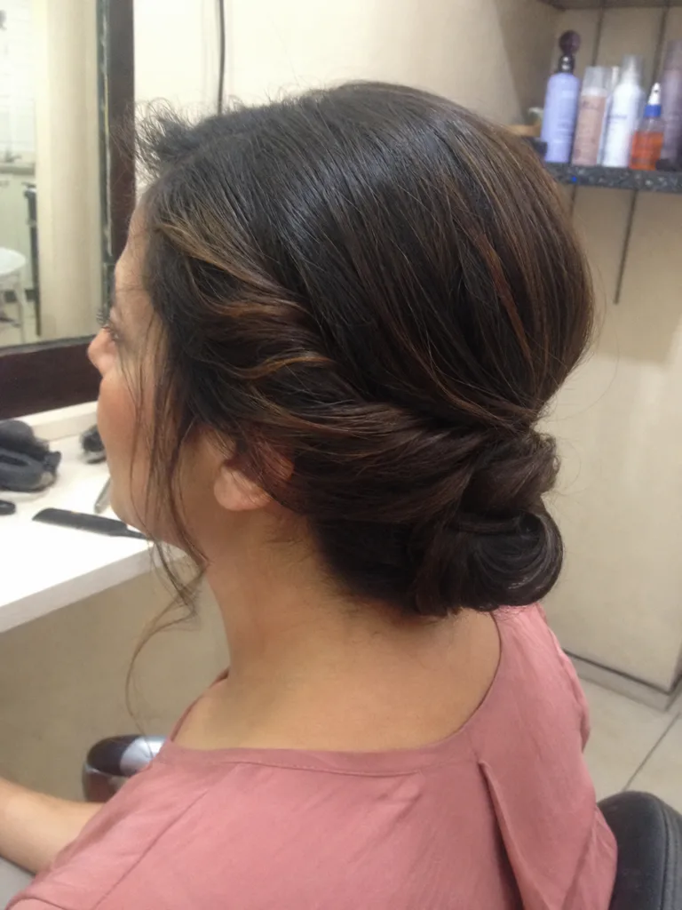 Twisted low bridesmaid updo with soft loose face-framing pieces.