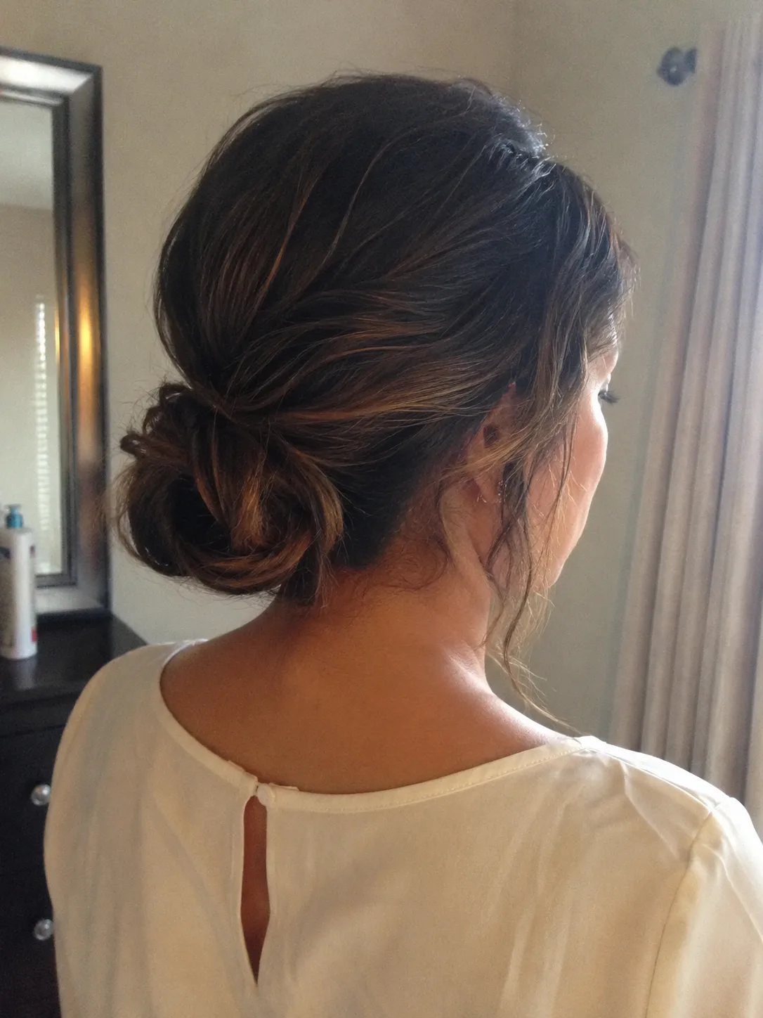 Wedding guest hairstyle with polished brunette waves and soft face framing