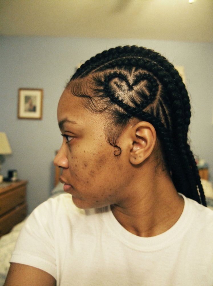 The hair is black and styled in long braids that extend down the back