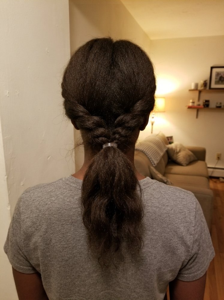 The hair is dark brown in color, with a smooth texture, and is long, extending down to the middle of the back.