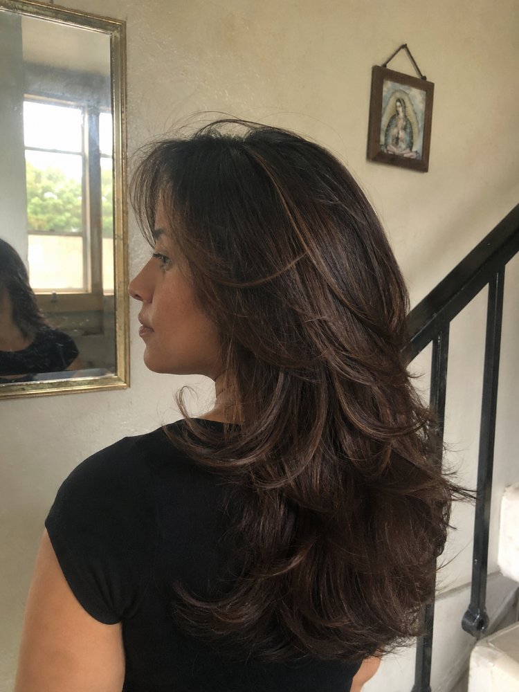 The hair is a dark brown color with subtle highlights, adding dimension and texture to the overall look.