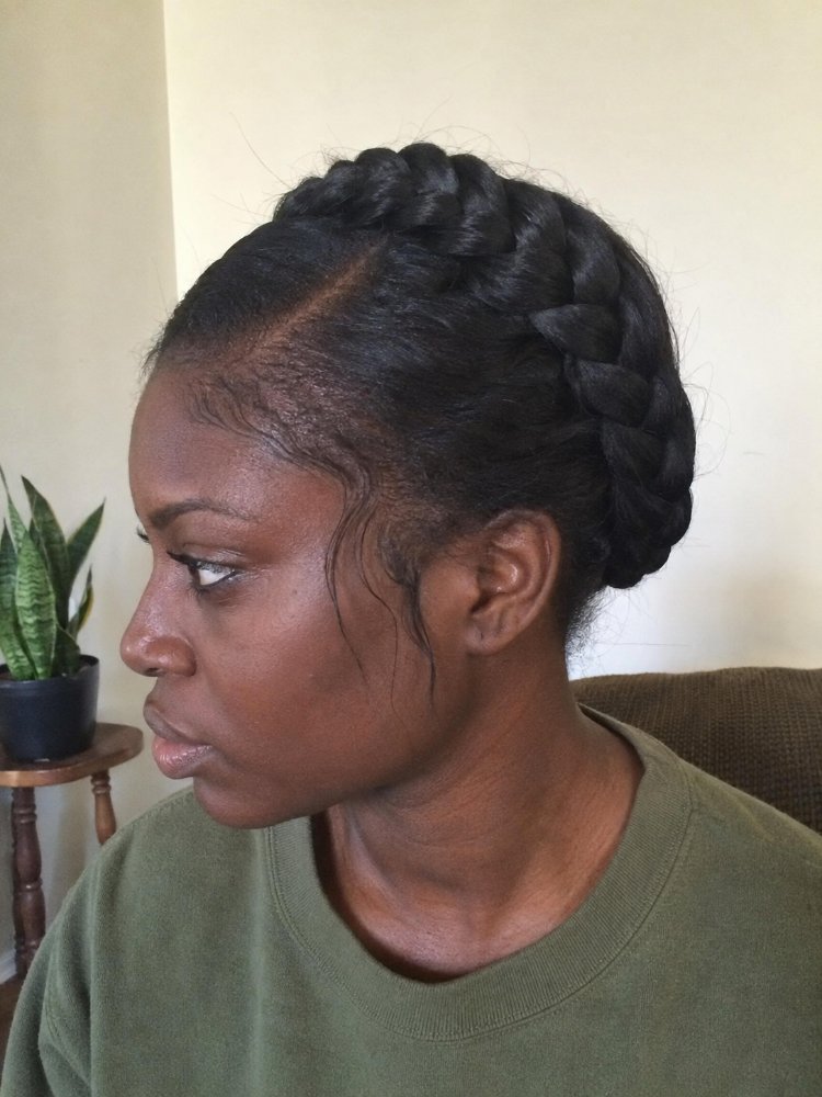 The hair is dark brown and styled in a French braid that wraps around the back of the head.