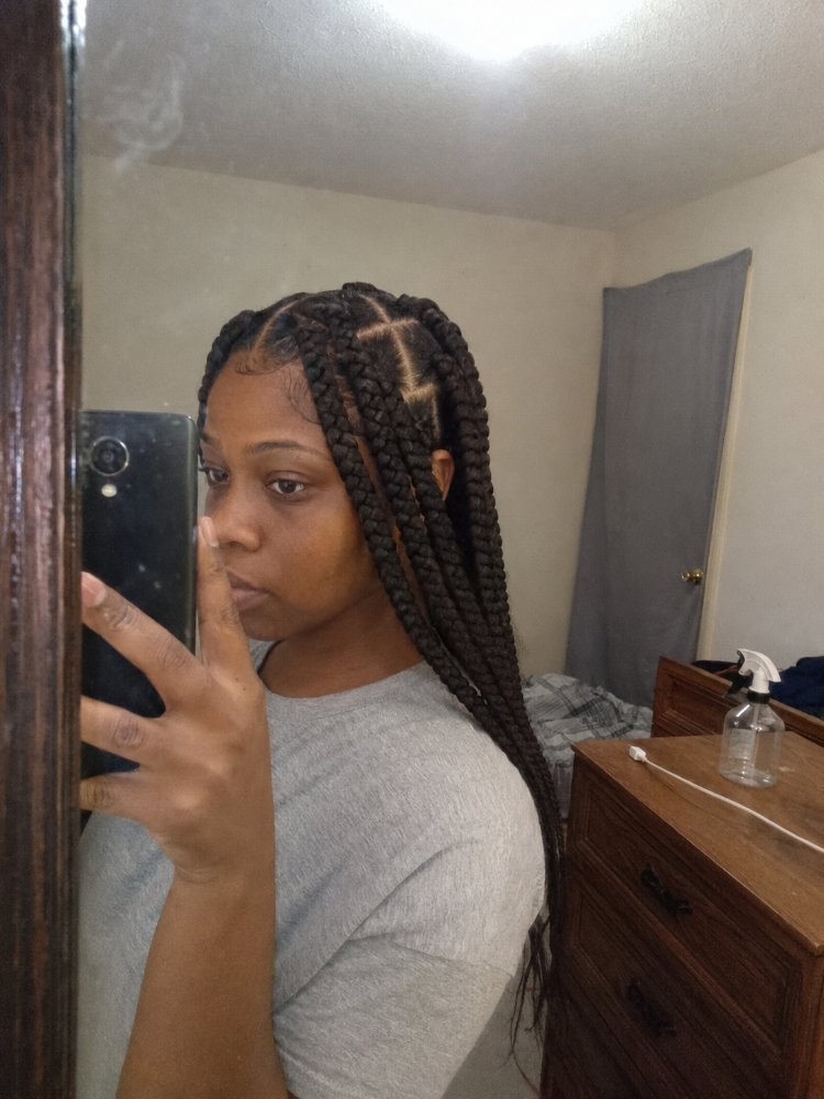The hair is dark brown and styled in large, long box braids that extend down to the lower back