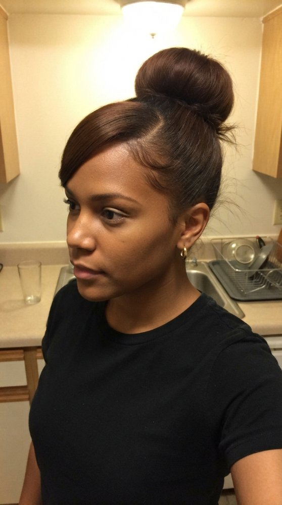 The hair is dark brown and styled in a sleek, high bun