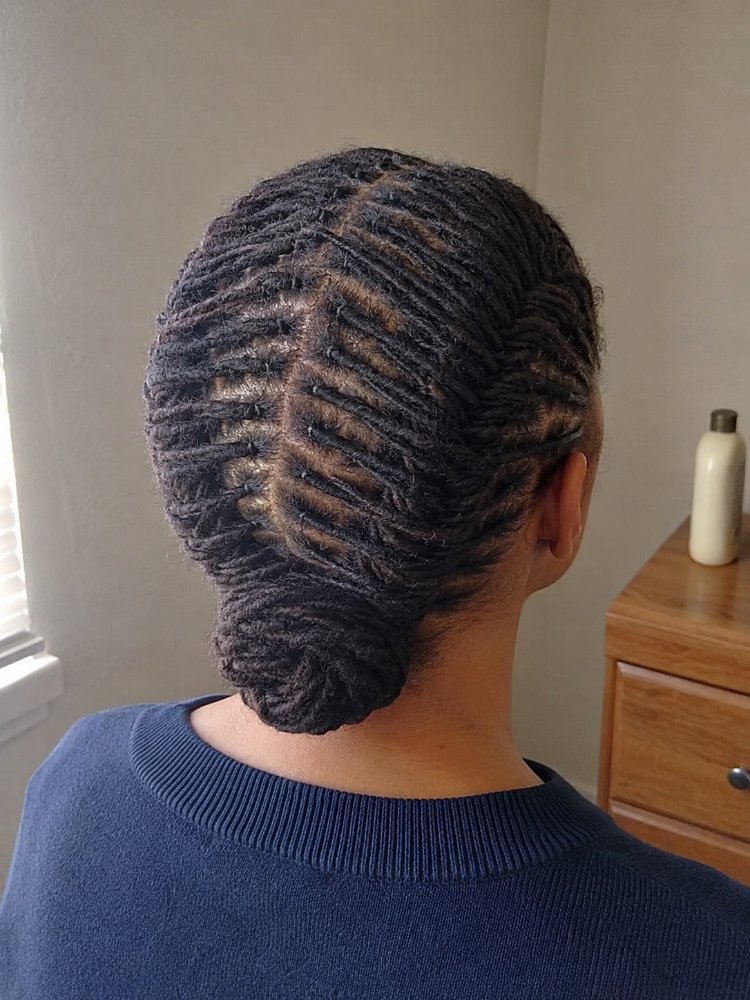 dark brown subtle shine styled The hair is dark brown with a subtle shine, styled in small, tightly coiled cornrows that are neatly gathered into a low bun. The texture appears to be thick and coarse