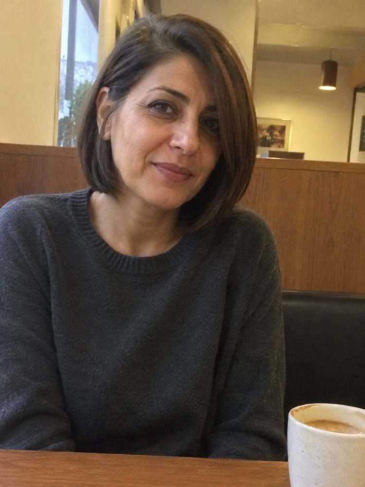 The hair is dark brown with a subtle, uniform color tone and a smooth texture. It falls just above the shoulders in a straight, blunt cut with visible layered styling, and frames the face with a sleek, angled silhouette. The hair appears to be free of dimensional color, with visible soft regrowth blending