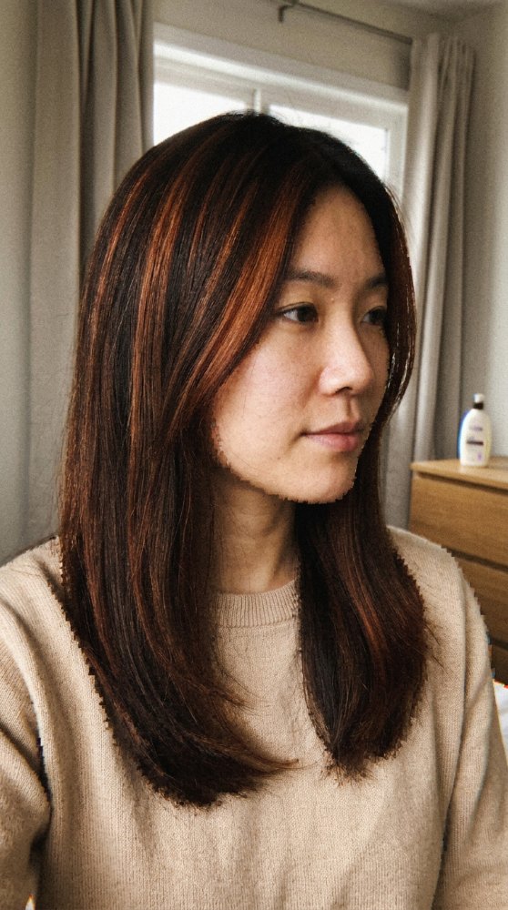 The hair is dark brown with subtle, warm, lighter brown highlights throughout, adding dimension and texture