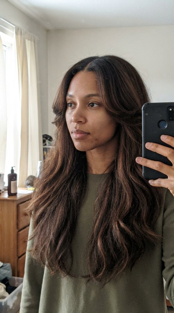 The hair is long, reaching down to the chest area, with a dark brown base color and subtle lighter brown highlights throughout, giving it dimension