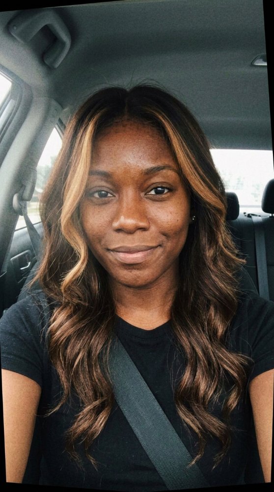 The hair is long, wavy, and dark brown in color with subtle highlights of lighter brown and blonde, particularly framing the face