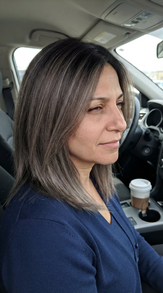 The hair is a medium to long length with a subtle, darker root area that transitions into a lighter, ash-blonde color towards the ends