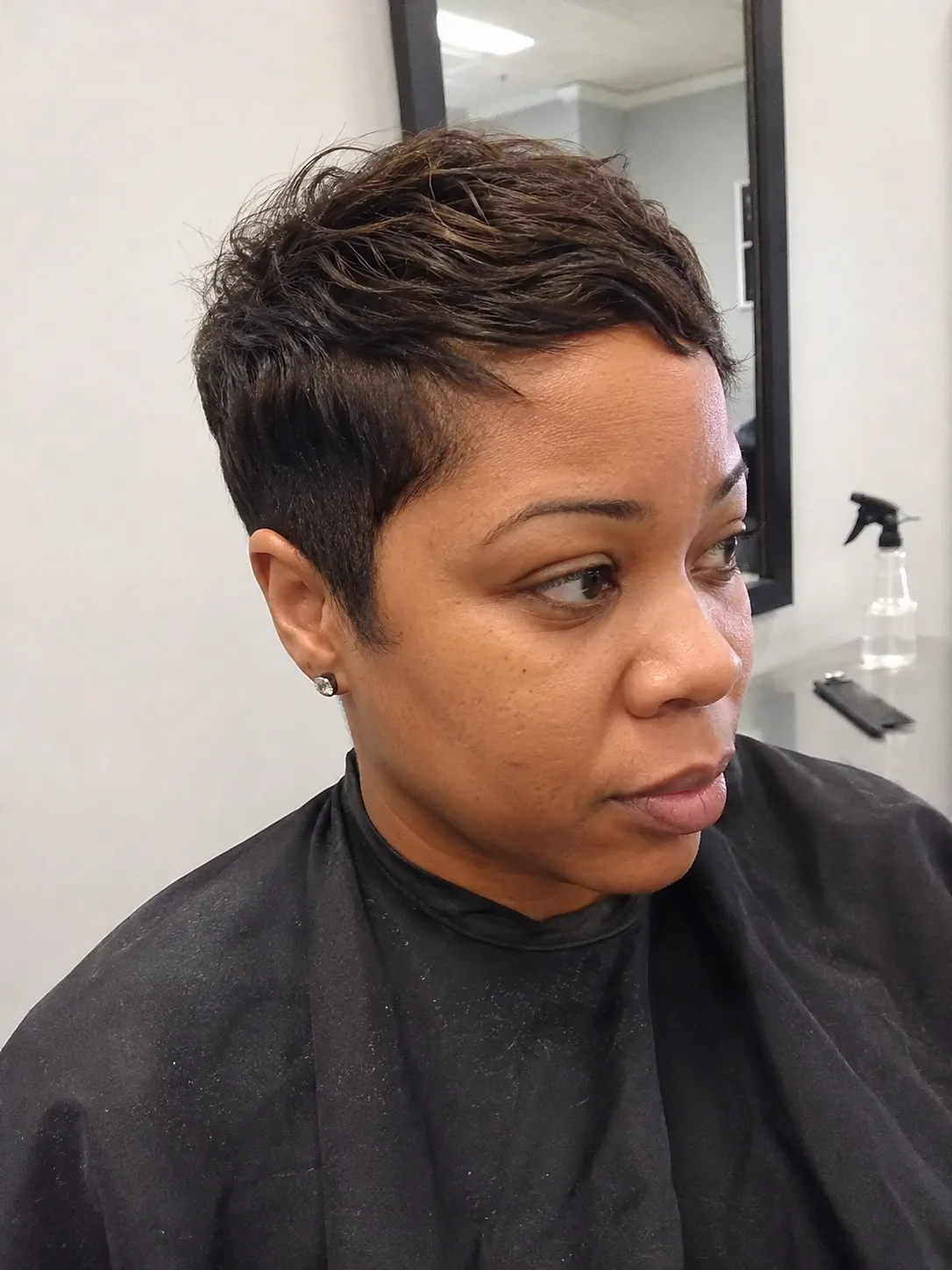 Asymmetrical pixie haircut with deep side part and sleek longer front section