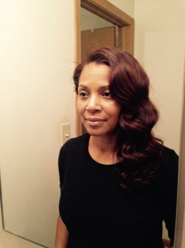 The hair is a rich, dark brown color with subtle waves and loose curls, falling to a medium length that reaches the mid-back area