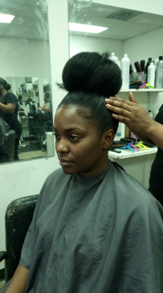 Black hair slicked back into a high bun with a smooth, flat hairline and glossy finish showing clean edge control.