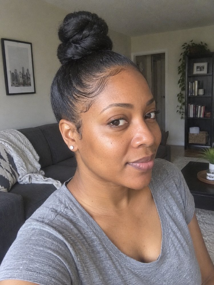 styled high bun appears black The hair is styled in a high bun and appears to be black in color. The edges of the hair are sleek and smooth, with a defined hairline, and there are visible layered styling. The hair texture seems to be smooth and possibly has a glossy finish