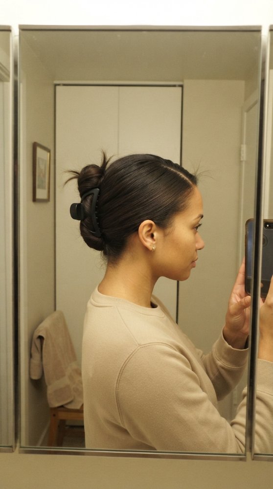 The hair visible in the is dark brown, pulled back into a low bun and secured with a black hair clip