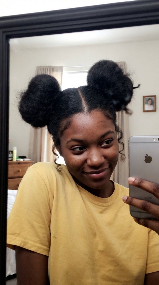 The hair visible in the is dark in color and is tightly coiled and dense in texture